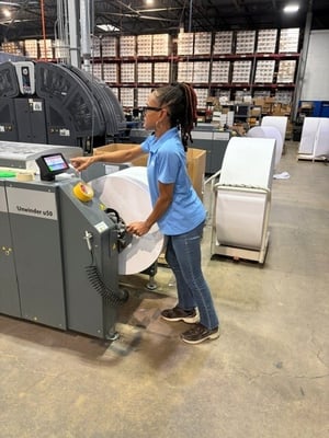 Renkim employee manages the print roll feed from the IntelliJet printer to the Epic mail inserter.